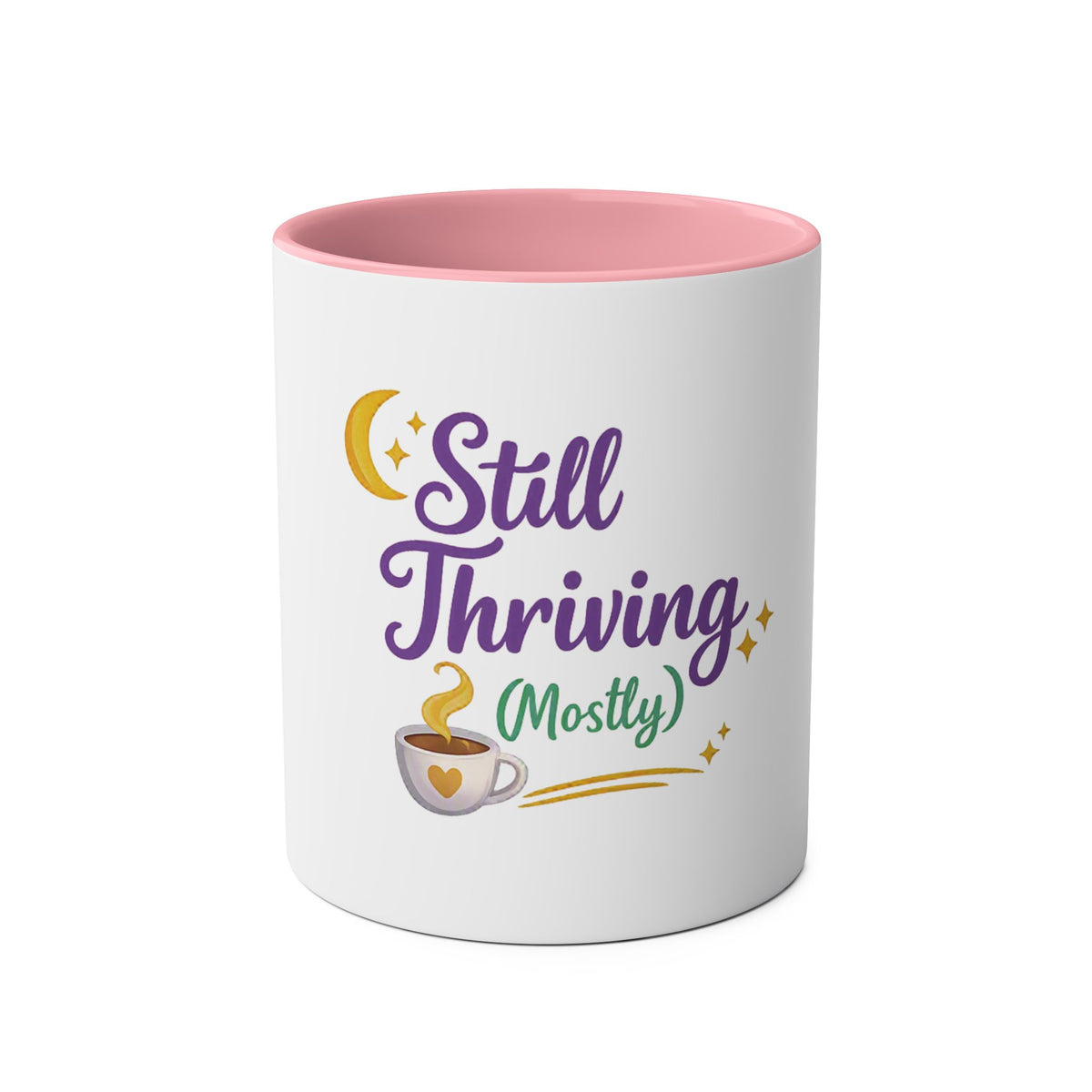 A white ceramic mug with a pink interior, featuring a graphic design on the front that reads 'Still Thriving (Mostly)' in purple and green lettering, accompanied by a yellow crescent moon, stars, and a small coffee cup illustration.
