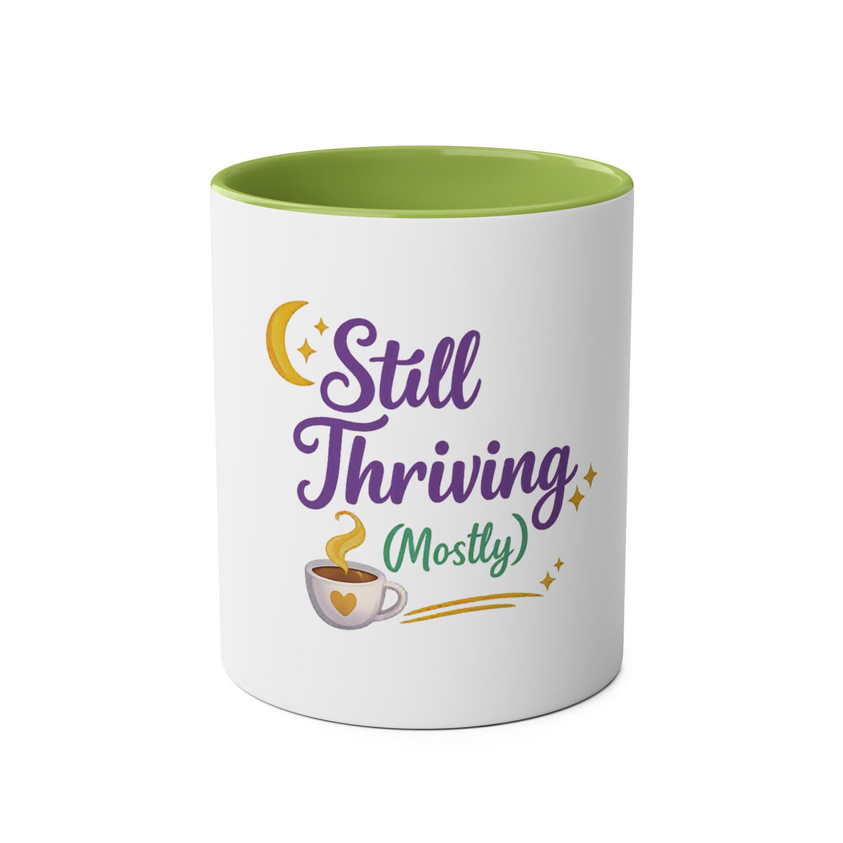 A white ceramic mug with a light green interior, featuring a graphic design on the front that reads 'Still Thriving (Mostly)' in purple and green lettering, accompanied by a yellow crescent moon, stars, and a small coffee cup illustration.