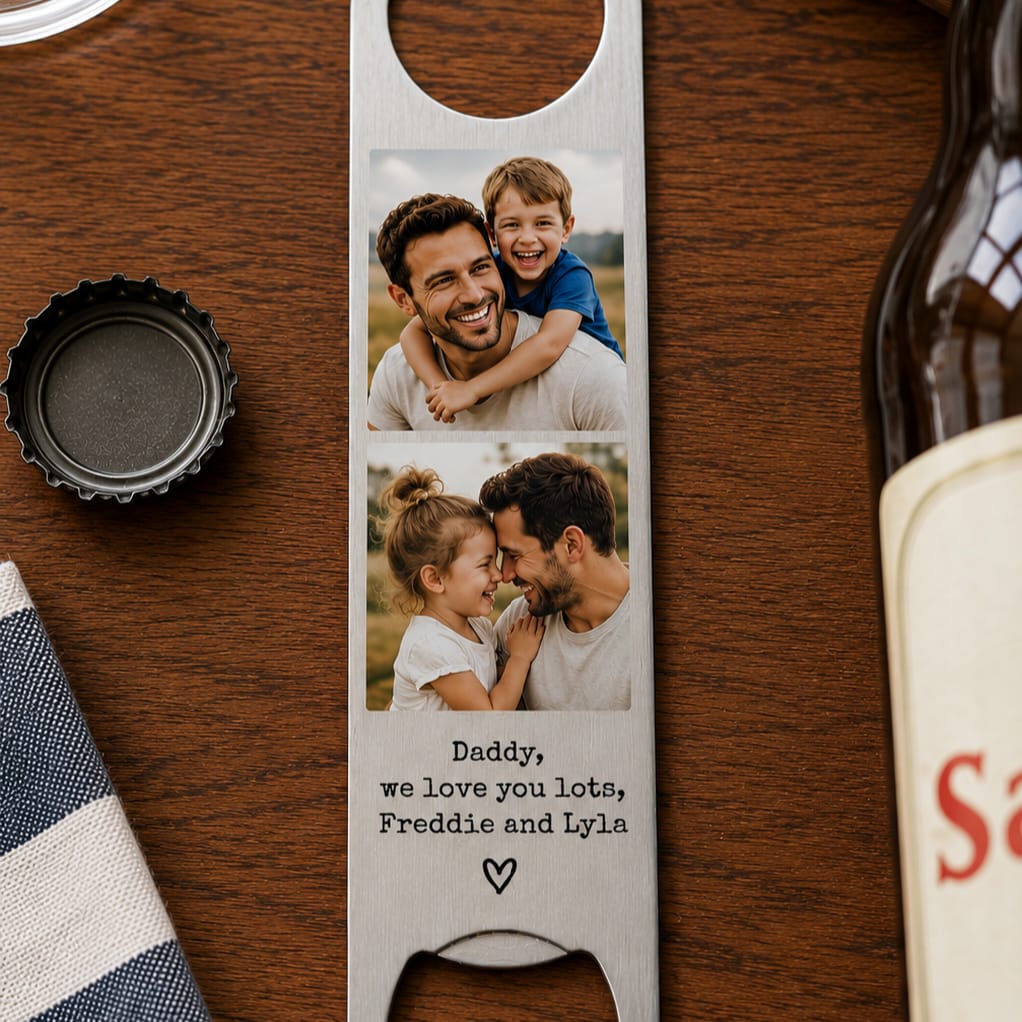 A personalized stainless steel bottle opener with a photo of a father and child and engraved text, displayed on a wooden table next to a bottle cap and a partial bottle.