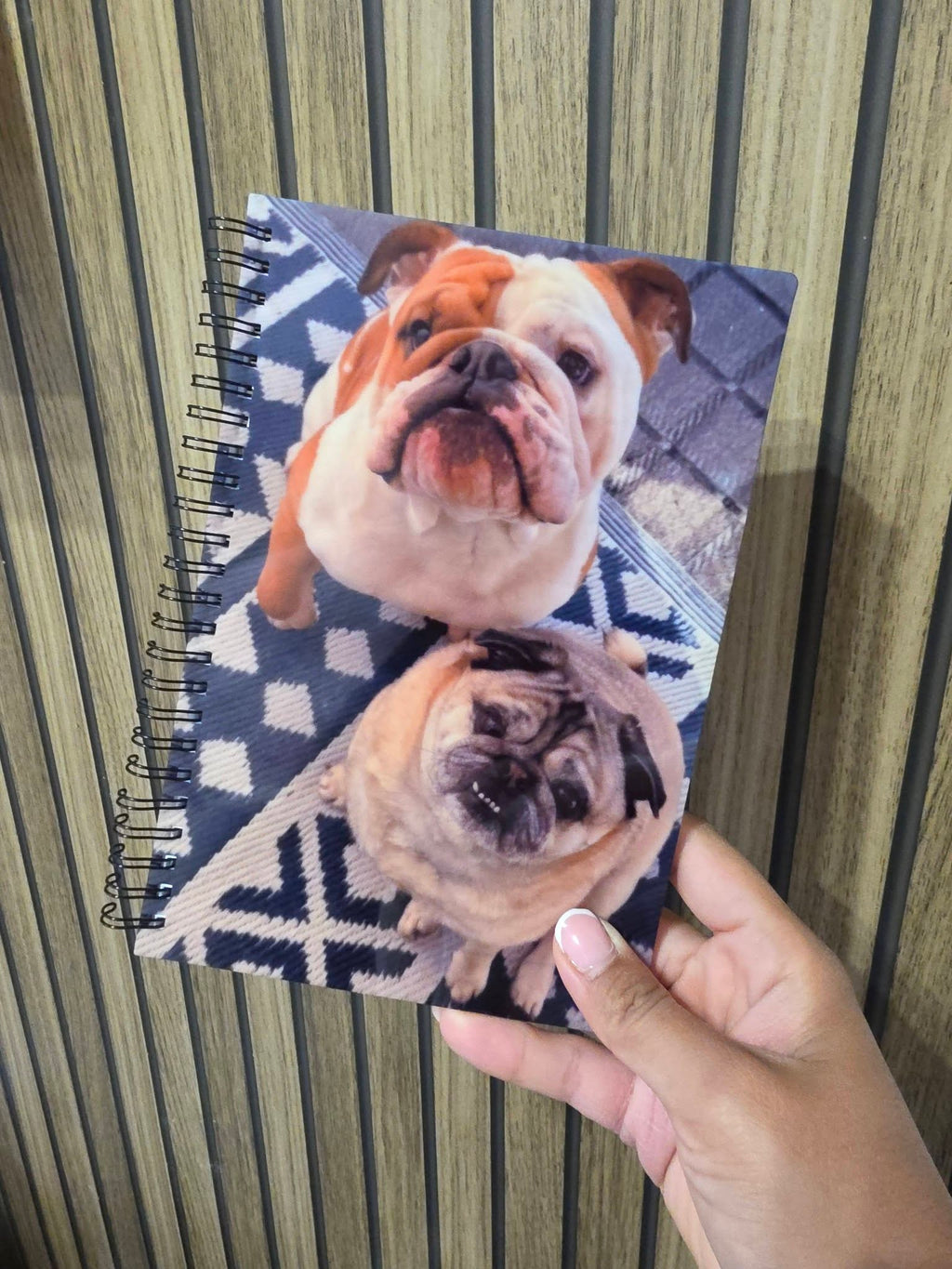 Notebook with a dog design held by a hand against a striped background